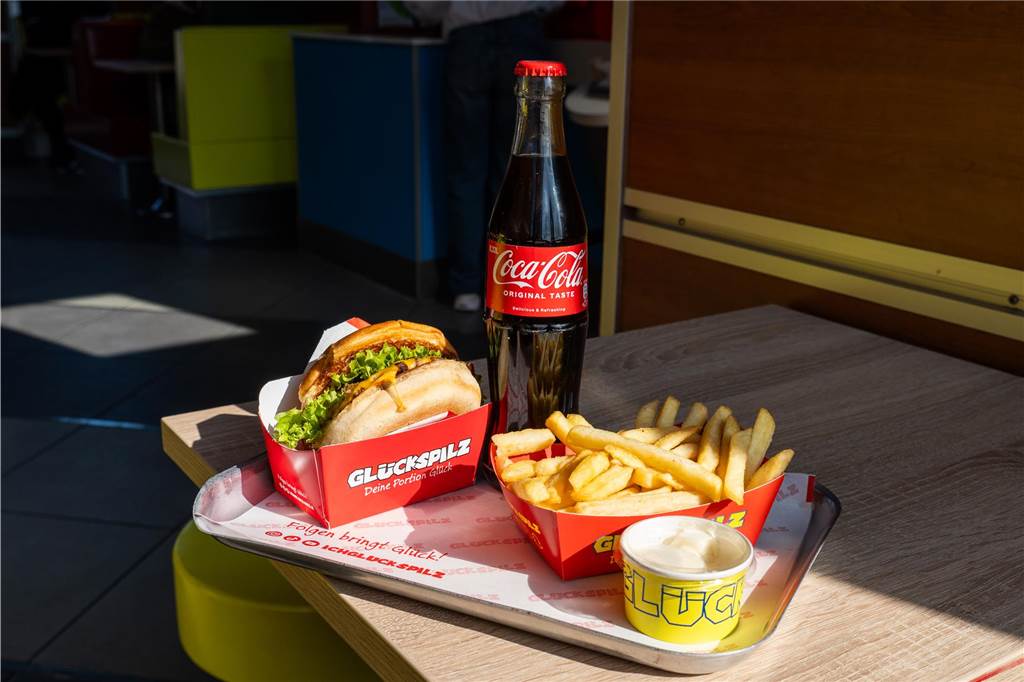 Top-Qualität oder nur Social-Media-Hype? Wir testen die Burger von „Glückspilz“ am Hauptbahnhof Ansicht von Burger, Pommes und Cola, die auf einem Tisch bei "Glückspilz" in Recklinghausen stehen.
