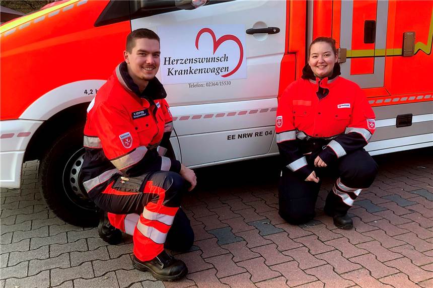 Halterner Malteser erfüllen Schwerkranken Herzenswünsche Rettungshelferin Sofie Gerdes und Rettungssanitäter Matthias Kemper vor dem neuen Herzenswunsch Logo.