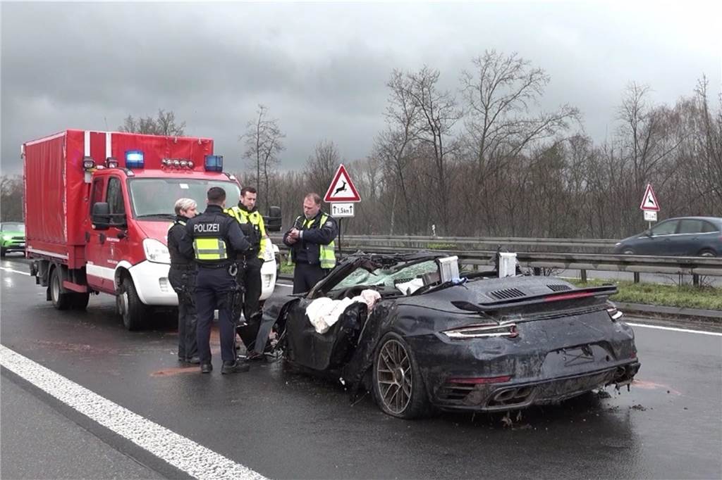 Mehrere Unfälle kurz hintereinander auf A3: Tote Polizisten stehen an dem Wrack eines Porsches auf der Autobahn 3.