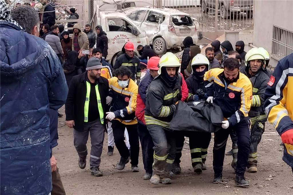 Rettungstruppen, die eine tote Person aus den Trümmern tragen. 