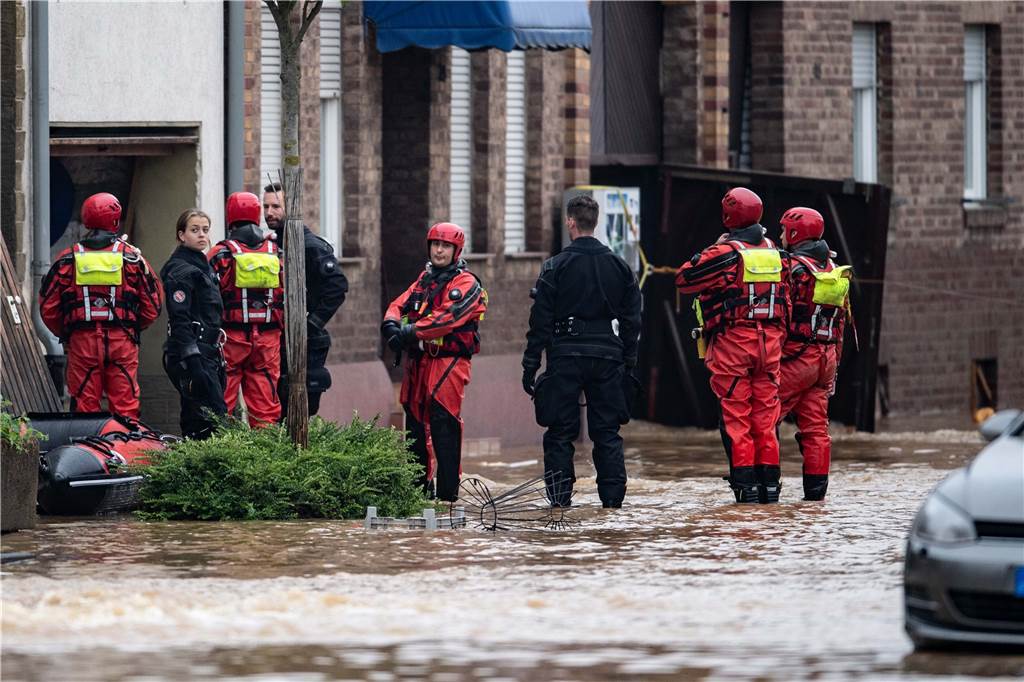 „Dieses Riesenloch“: Erftstadt und die bangen Stunden der Flut Rettungsschwimmer und Polizeitaucher stehen in einer überfluteten Straße im Ortsteil Blessem.