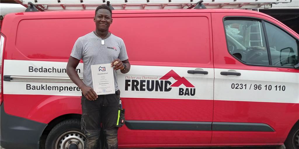 Lange Wartezeit: Dortmunder Auszubildender geht durch Bürokratie-Hölle Robert Duolamou steht vor dem Firmenwagen der "Freund Bau GmbH Dortmund", aus Lütgendortmund, und hält sein Abschlusszeugnis in der Hand.