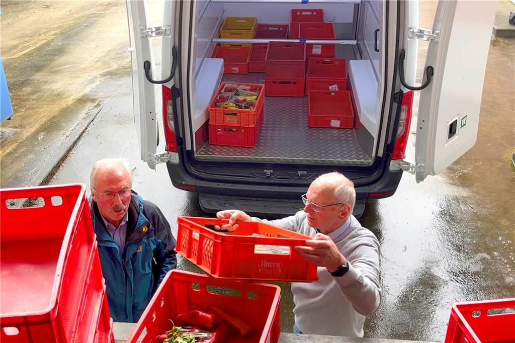 Ehrenamtliche Mitarbeiter der Tafel verladen Kisten.