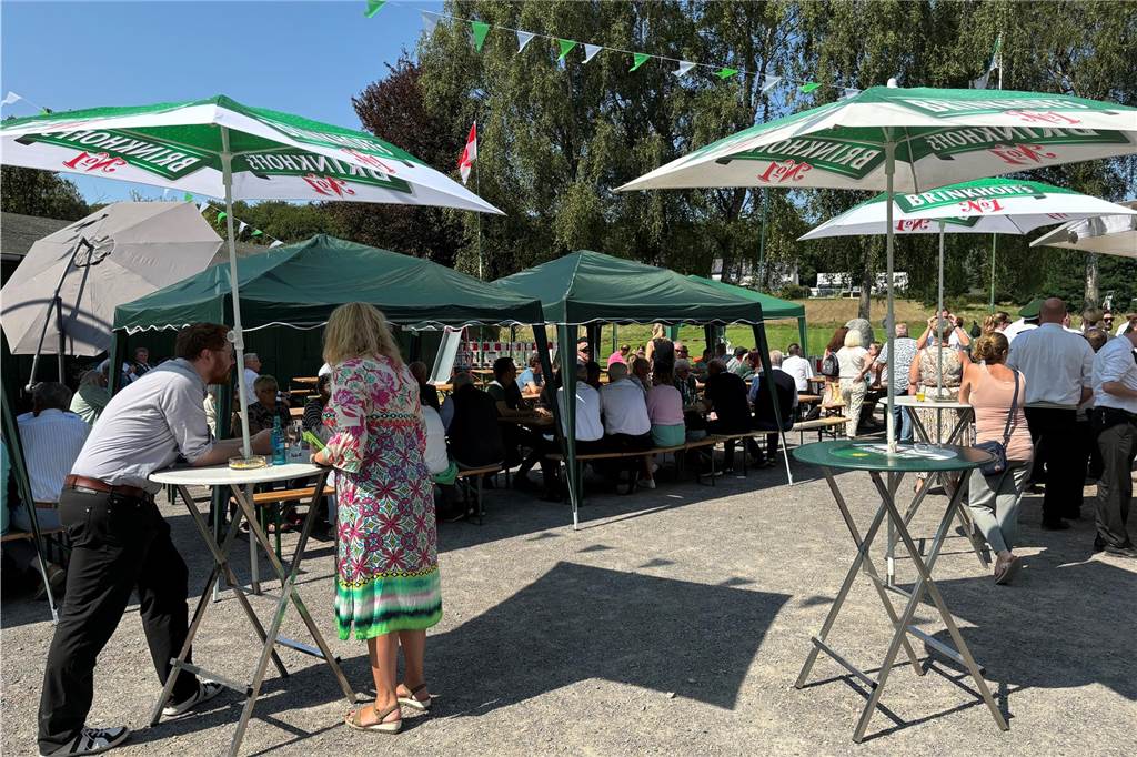 Die Besucher stehen an Stehtischen oder sitzen an Tischen.