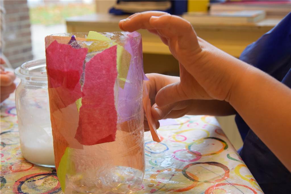 Till (5) zeigt uns, wie man eine bunte Last-Minute-Laterne bastelt Schicht für Schicht wird das Transparentpapier auf der Flasche befestigt.