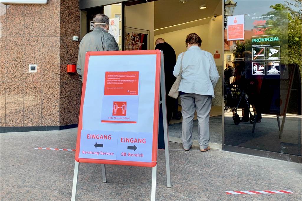 Security und lange Schlange vor der Sparkassen-Filiale in Aplerbeck Schilder machten die Kunden auf die verschiedenen Eingänge aufmerksam.