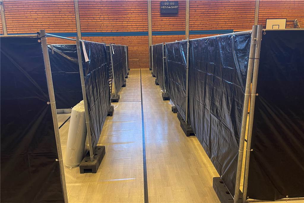 Blick in eine Notunterkunft in Dorsten: Freiheit auf 27 Quadratmetern Schmale Gänge und mit Folie bezogene Bauzäune trennen die Kabinen in der Notunterkunft Josefhalle voneinander.