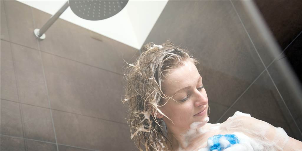 Mit Deckel kochen, ohne Vorheizen backen: Wie viel Geld spart man dabei wirklich? Eine Frau steht unter der Dusche.