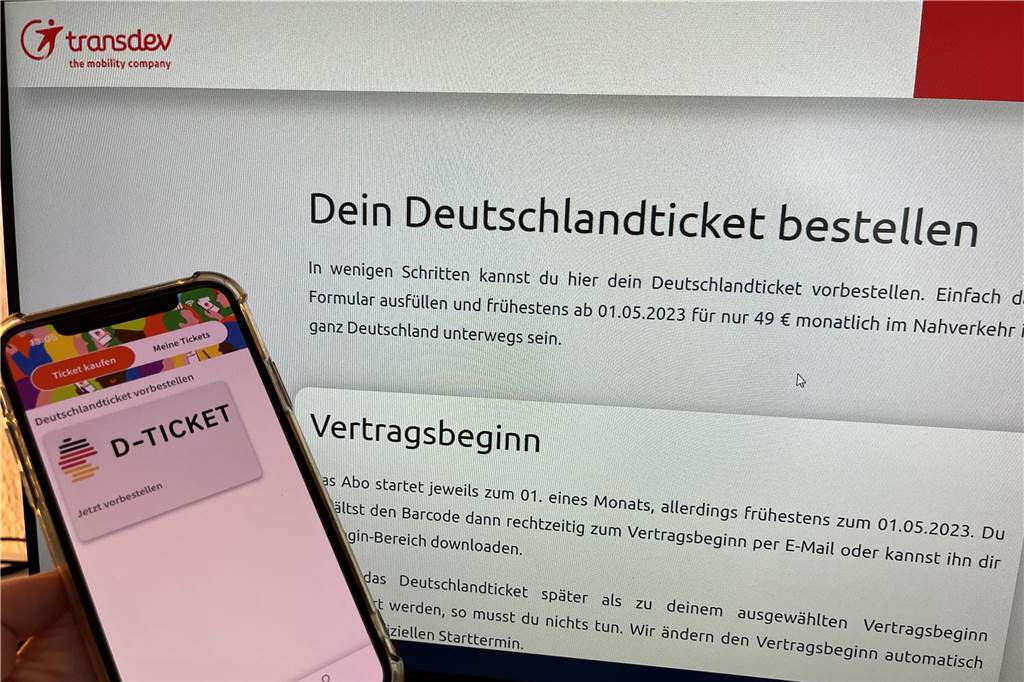 Handy mit Deutschland-Ticket vor dem PC-Bildschirm, auf dem der Online-Shop abgebildet ist.