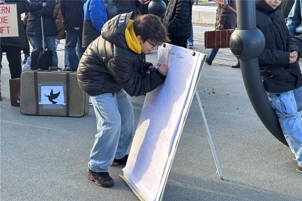 Ein Schüler schreibt auf ein Flipchart, welches auf dem Platz vor dem Bahnhof gestellt wurde. 