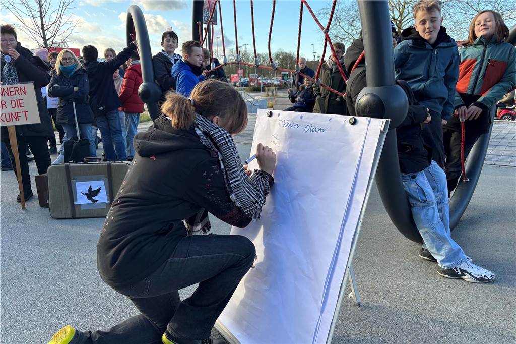 Eine Schülerin schreibt auf ein Flipchart, welches auf dem Platz vor dem Bahnhof gestellt wurde. 