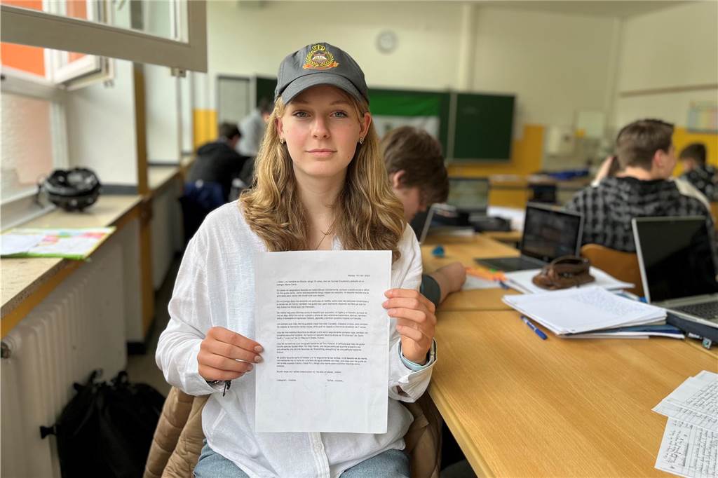 Schülerin Nelly (13) hält ihren Brief vor sich und trägt eine Kappe mit dem Wappen der Partnerschule.