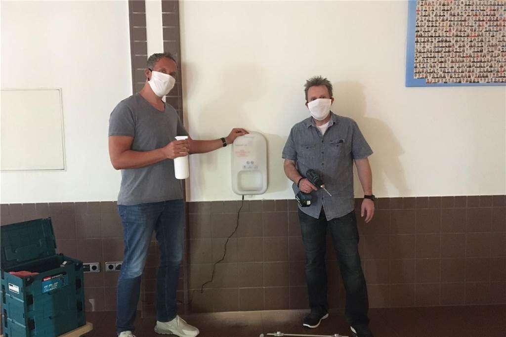 Schulen in Werne starten mit Schutzmasken, Einbahnstraßen und viel Abstand Schulleiter Thorsten Schröer und Hausmeister Westbomke montieren einen neuen Desinfektionsmittel-Spender in der Aula des St.-Christophorus-Gymnasiums.