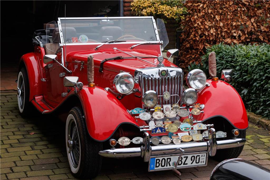 VW Käfer wird zum „Oldtimer“: Karl-Heinz Doods baut Kopie in Handarbeit Ein rotes Auto steht in der Einfahrt einer Garage.