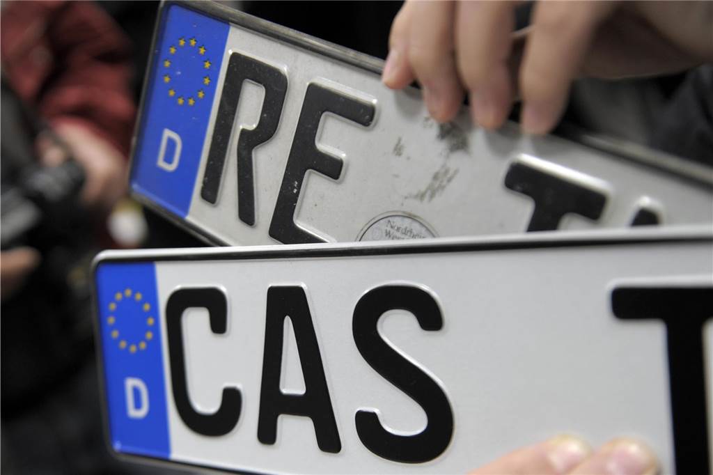 Name, Alter, Größe: Was schreibt Google über Castrop-Rauxel? Ein Mann hält zwei Nummernschilder mit den Kennzeichen RE und CAS in der Hand