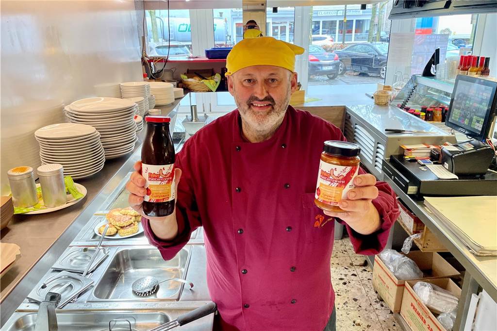 Peter Finke mit Currywurst und -soße in seinem Ladenlokal
