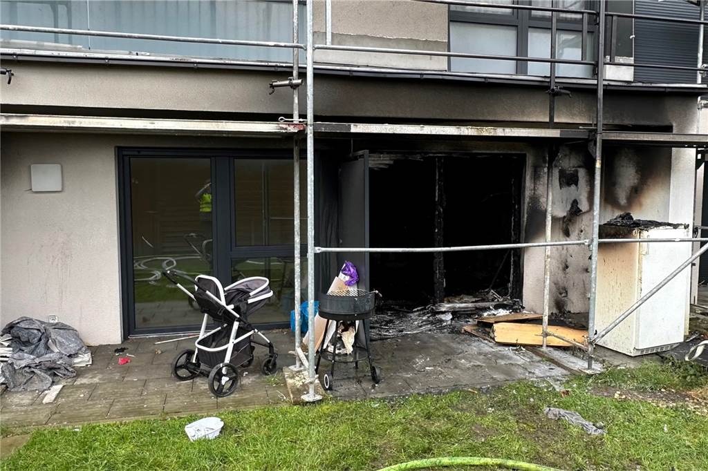 Feuer in Mengeder Mehrfamilienhaus: Wohnung völlig zerstört Ein Kinderwagen und ein Grill stehen auf einer Terrasse, die von einem Feuer schwer beschädigt wurde.