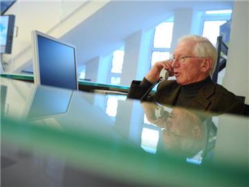 Senior Hugo Kleine telefoniert während seiner Arbeit am Empfang einer Kieler Behörde: Mehr und mehr Deutsche arbeiten auch noch im Rentenalter. Foto: Christian Charisius