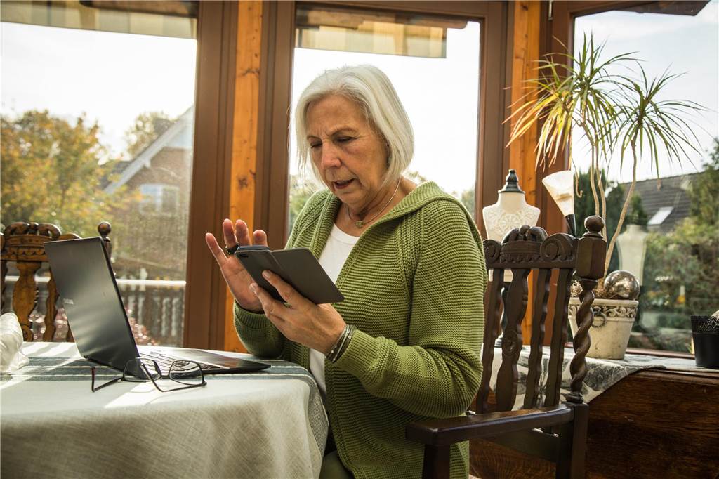 Schockanrufe und Internetkriminalität: Erinnerungswürfel warnt Senioren Eine Seniorin tippt auf ein Handy.