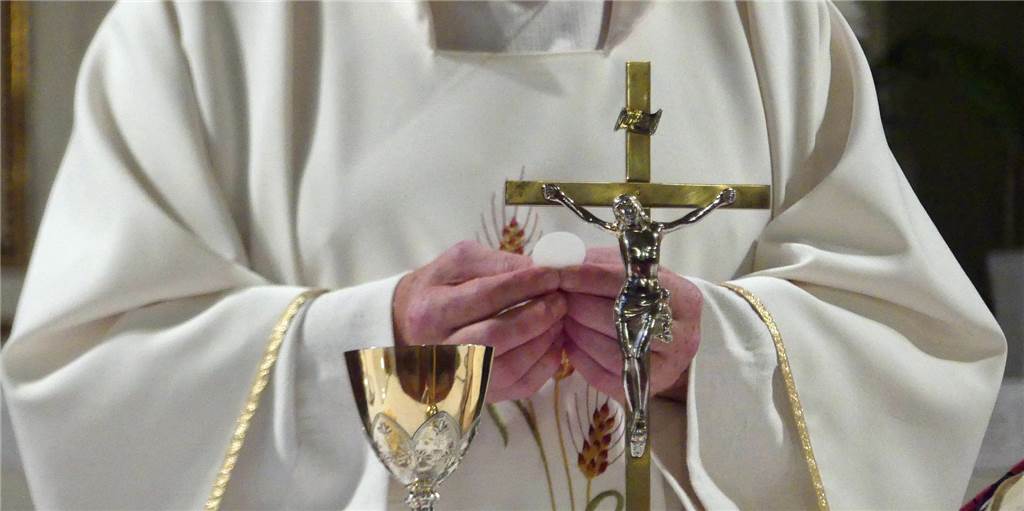 Zölibat, nein danke: Ein Werner Pfarrer und sein Verhältnis zur „Mönchshure“ Ein Pfarrer hält eine Oblate in den Händen.