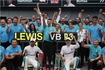 Sieger Lewis Hamilton und sein Teamkollege Valtteri Bottas (Dritter im Rennen) posieren mit dem Team von Mercedes. Foto: Antonio Calanni/AP