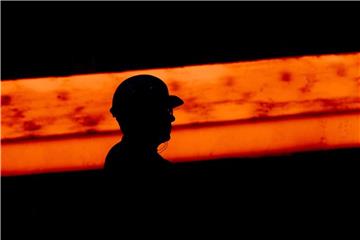 Silhouette eines Stahlarbeiters vor einer glühenden Bramme in Salzgitter. Foto: Julian Stratenschulte