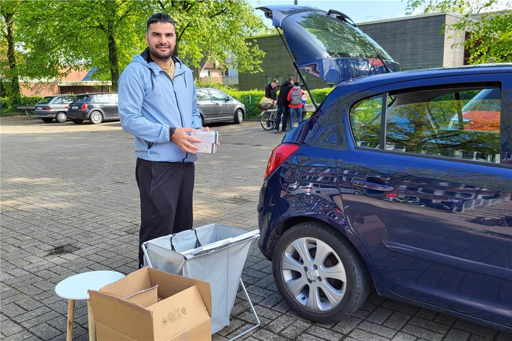 Ein Händler steht an seinem Auto.