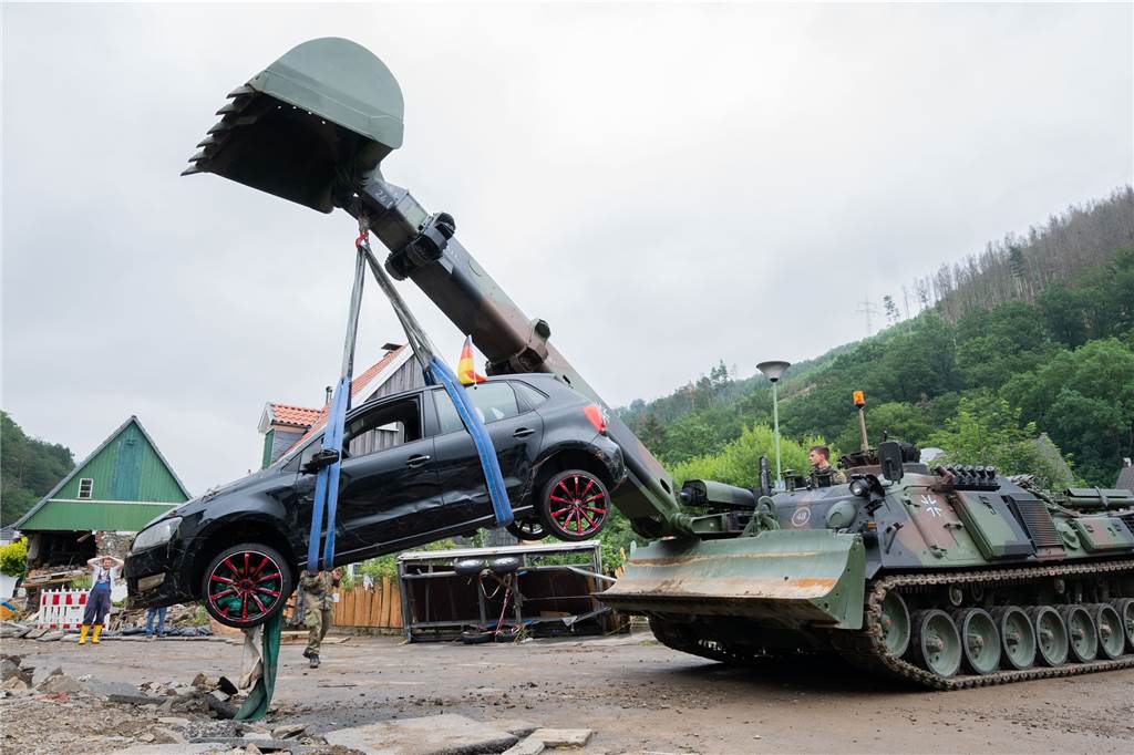 Soldaten der Bundeswehr bergen mit einem Pionierpanzer ein zerstörtes Auto bei den Aufräumarbeiten der schweren Unwetterschäden in Hagen-Hohenlimburg. 