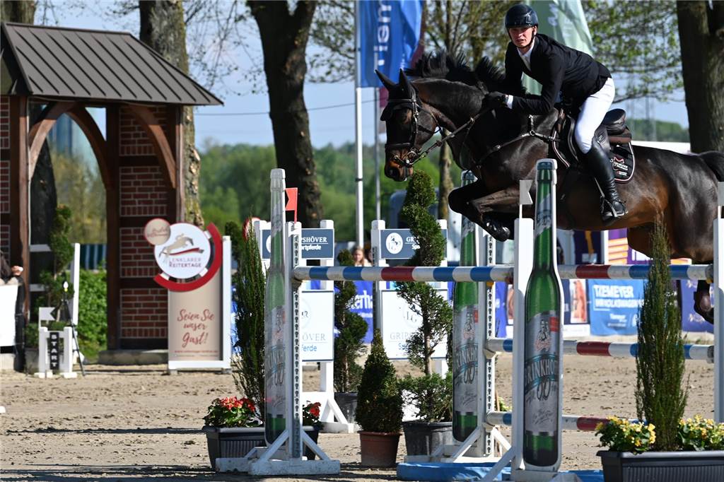 Ein Reiter springt mit einem Pferd über einen Sprung.