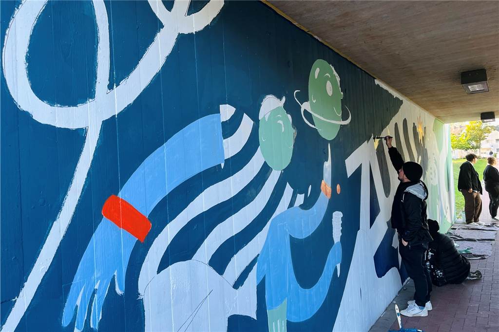 Sport, Natur und 1. Mai: Künstler und Jugendliche gestalten Unterführung am WUP Künstler malen an den Graffitis an der Wand.