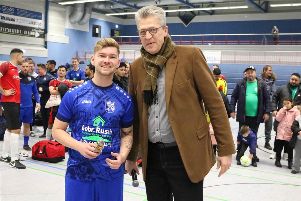 Torschützenkönig der HSM Bergkamen mit Sonntagsschüssen Steven Potthoff, Torschützenkönig der HSM Bergkamen und Bürgermeister Bernd Schäfer blicken in die Kamera. Potthoff hält einen Pokal in der Hand.