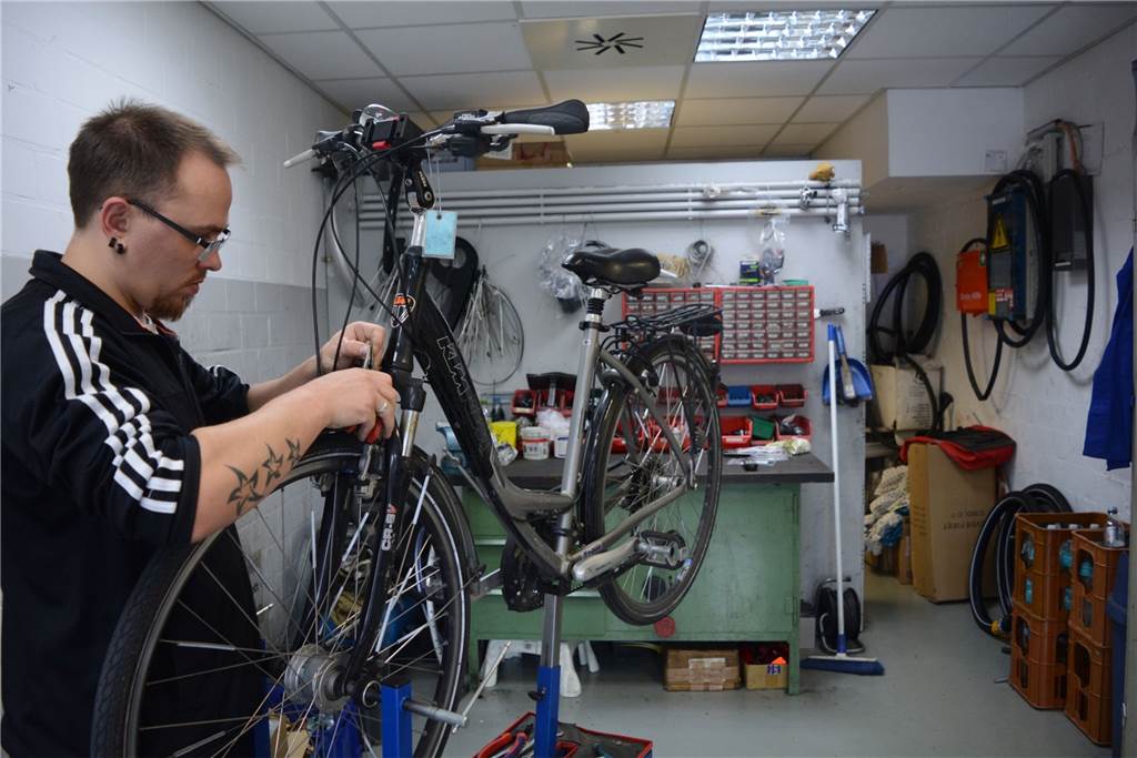 Sichere Stellplätze, Reparaturservice und Arbeitsgelegenheiten - das bieten Radstationen Sven Pragal schraubt an einem Rad, das zur Reparatur abgegeben wurde.