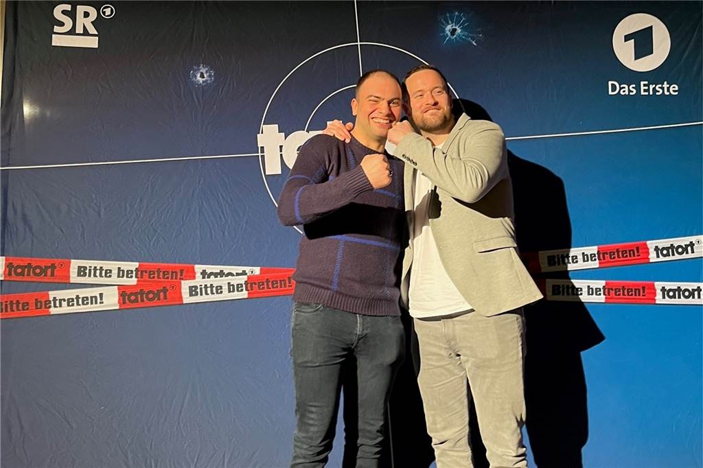 Ex-Werner spielt im ARD-Tatort mit: Tamer Tahan schlüpft in gefährliche Rolle Tamer Tahan und Schauspiel-Kollege Lorris Andre Blazejewski stehen vor einer Tatort-Wand.