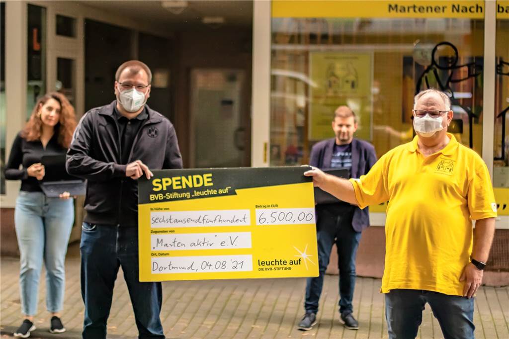 Zum Schulstart: BVB unterstützt Schulprojekt im Dortmunder Westen Thomas Klein (BVB, l.) überreichte Axel Wolff einen Scheck für das neue Projekt „Help Point“. Projektmitglieder sind unter anderem Fidan Keskin (l.) und Leonid Zeldin (hinten.).