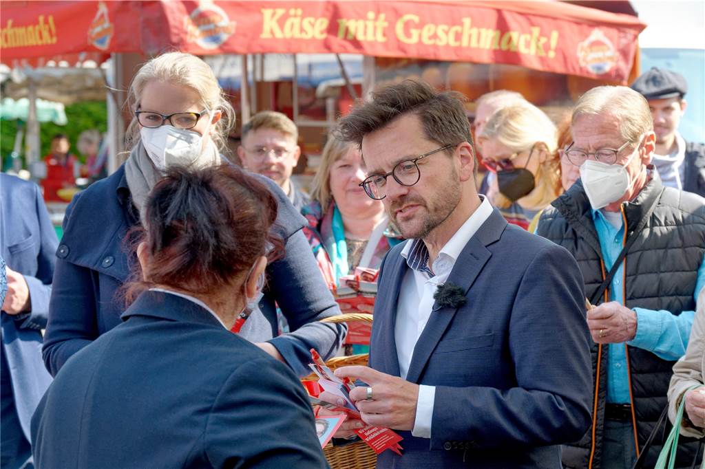 Frikadelle mit Kakao: Wie Wüst und Kutschaty Wahlkampf machen Thomas Kutschaty, Spitzenkandidat der SPD zur Landtagwahl in Nordrhein-Westfalen verteilt auf einem Markt in Leverkusen- Opladen Werbematerial.