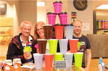 Thomas Lohmann, Sandra Burbank und Lars Hitscher vom Dorfladen stellen den FairCup Mehrwegbecher vor.