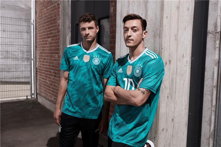 Spezieller WM-Slogan für Mission Titelverteidigung Thomas Müller (l.) und Mesut Özil im grünen Auswärtstrikot, mit dem Deutschland in diesem Jahr den Titel verteidigen will.