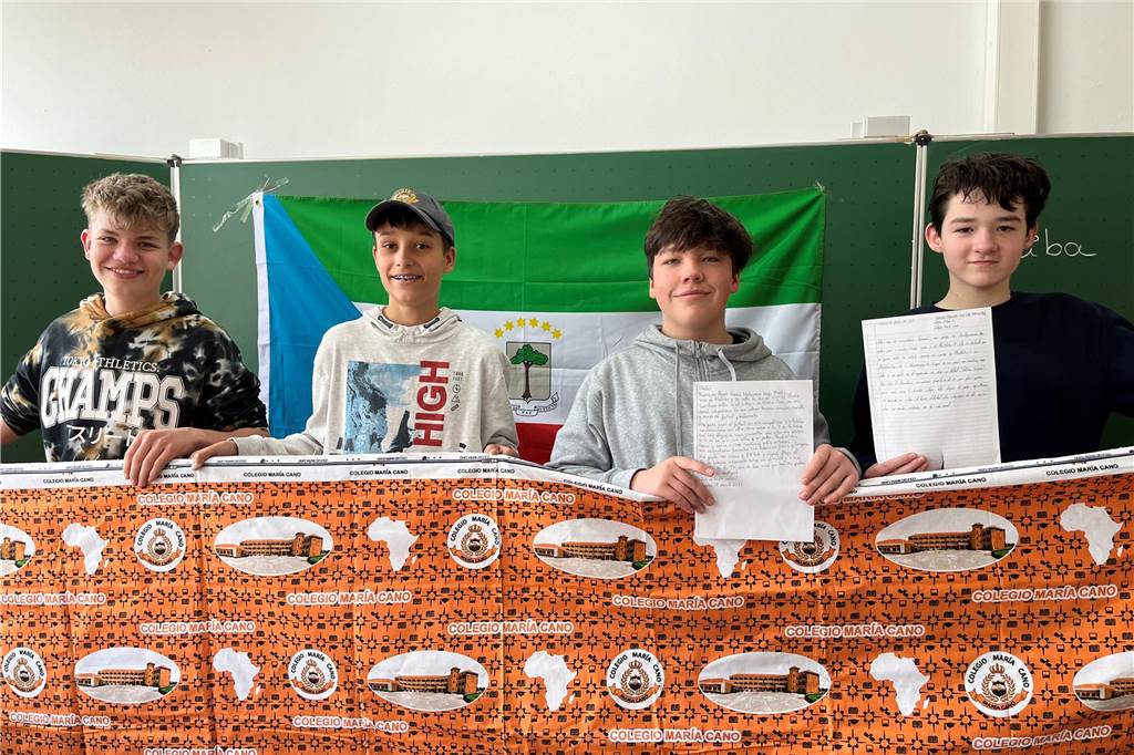 Timon, Jan-Luca, Keno und Erik (v.l.n.r.) halten ihre Briefe und einen Stoff vom Colegio María Cano in der Hand.