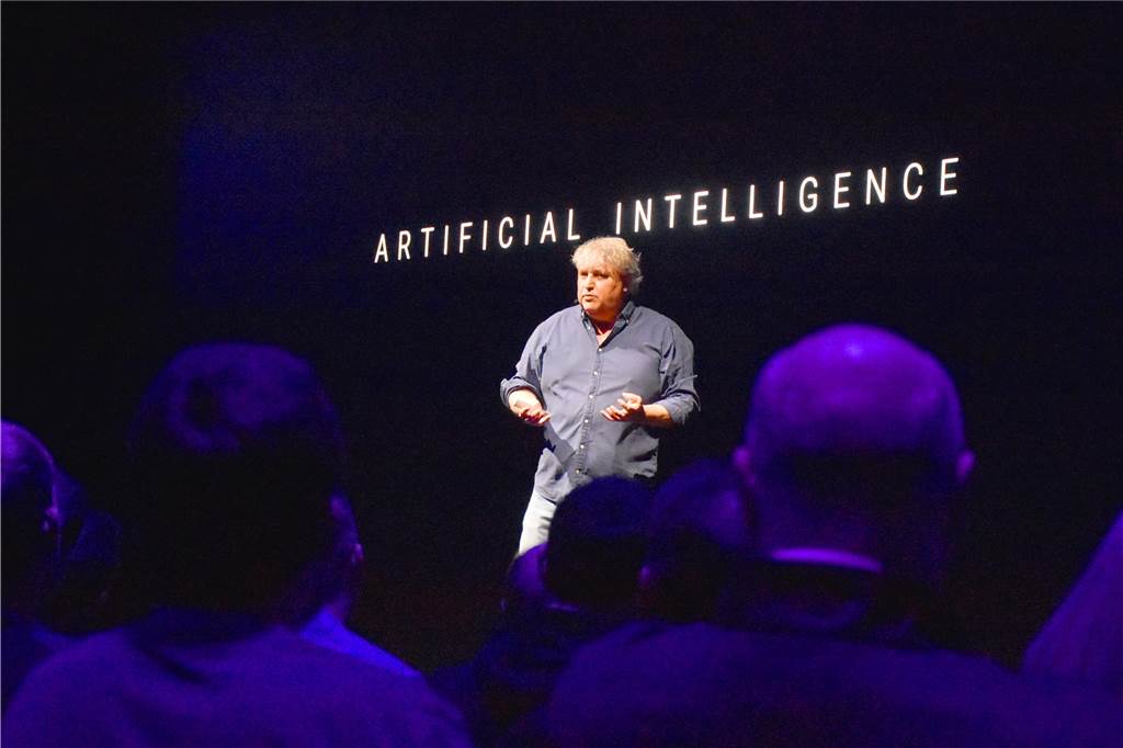 Tobias Groten steht vor einer dunklen Monitorwand mit der Aufschrift "Artificial Intelligence"