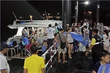 Touristen, die von einem sinkenden Boot gerettet worden sind, werden ans Festland begleitet. Foto: Thailand Royal Police/AP