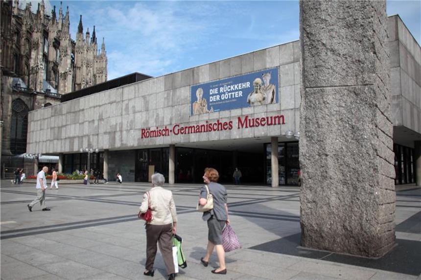 Touristen gehen über den Roncalli-Platz am Römisch-Germanischen Museum vorbei. Foto: Oliver Berg/Archiv