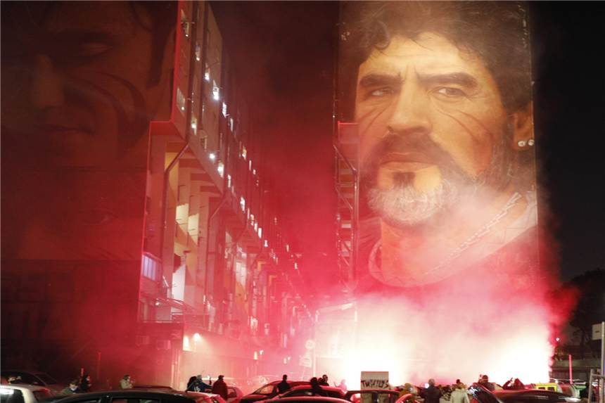 Gedenkminute für Maradona – BVB-Sportdirektor Zorc erinnert sich an Duell Trauernde stehen in Neapel unter einem Wandgemälde des Straßenkünstlers Jorit mit der Darstellung von Diego Maradona und zünden Leuchtfackeln an.