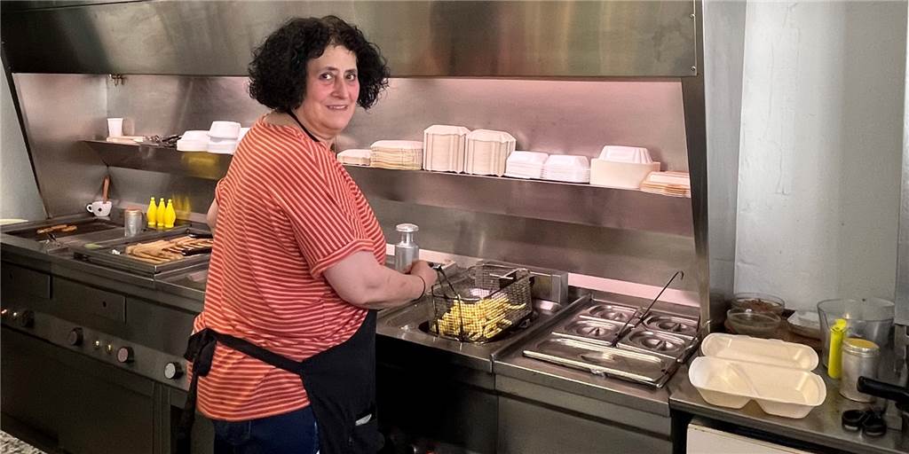„Tag der Pommes“: Für 1,20 Euro gibt es den Snack schon lange nicht mehr Die Imbiss-Besitzerin hält die Pommes, die gerade aus der Fritteuse kommen.