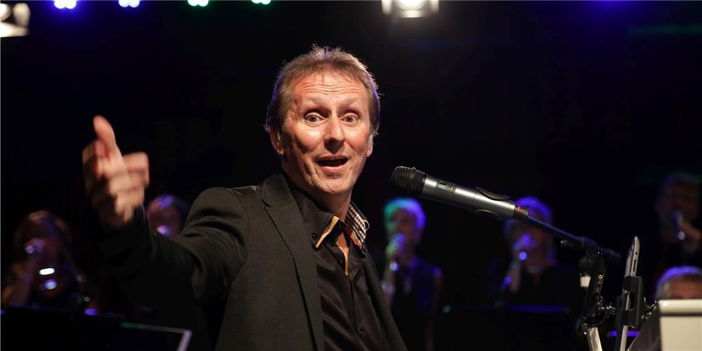 Udo singt Udos Lieder: Udo-Jürgens-Konzert in Erle Udo Hotten sitzt hinter einem Klavier und streckt einen Arm aus.