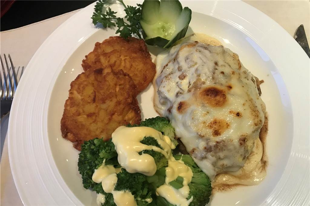 Auch ein Steakhaus kann vegetarisch sein Über dem Fleisch liegt eine Schicht aus gerösteten Zwiebeln in Sauce Hollandaise und Käse.