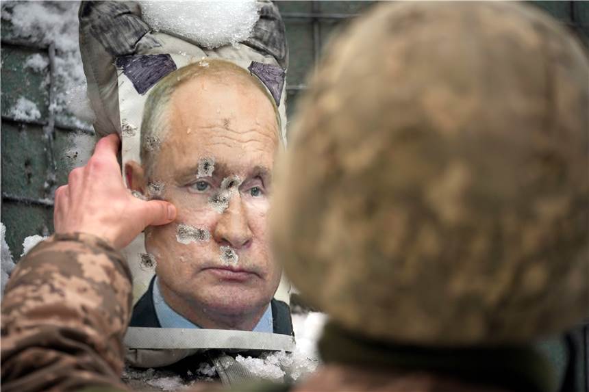 Ukraine, Luhansk: Ein ukrainischer Soldat justiert ein von Kugeln durchlöchertes Bild des russischen Präsidenten Putin.
