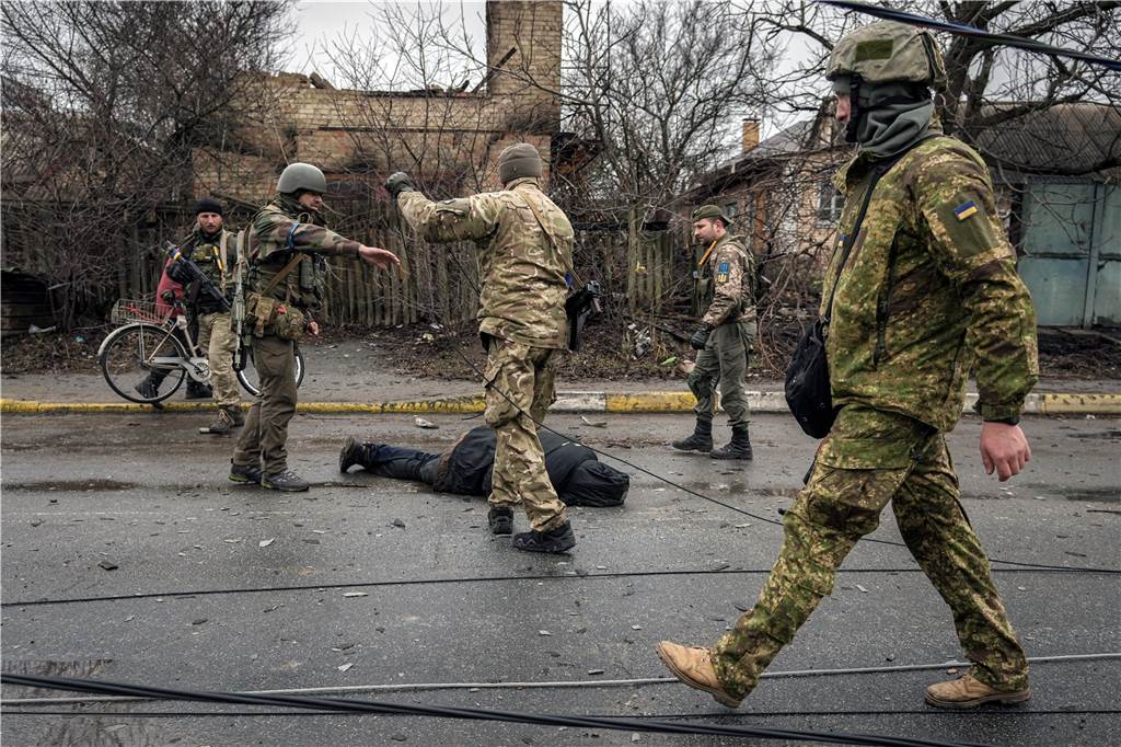 Die Kriegsverbrechen von Butscha: Putins Truppen hinterlassen nur den Tod Ukrainische Soldaten befestigen ein Kabel an der Leiche eines Zivilisten, während sie in dem ehemals russisch besetzten Kiewer Vorort Butscha nach Sprengfallen suchen. Der ukrainische Präsident Selenskyj warnte, dass die sich zurückziehenden russischen Truppen Minen, Ausrüstung und sogar die Leichen der Getöteten zurücklassen, wodurch eine katastrophale Situation für die Zivilbevölkerung entsteht.