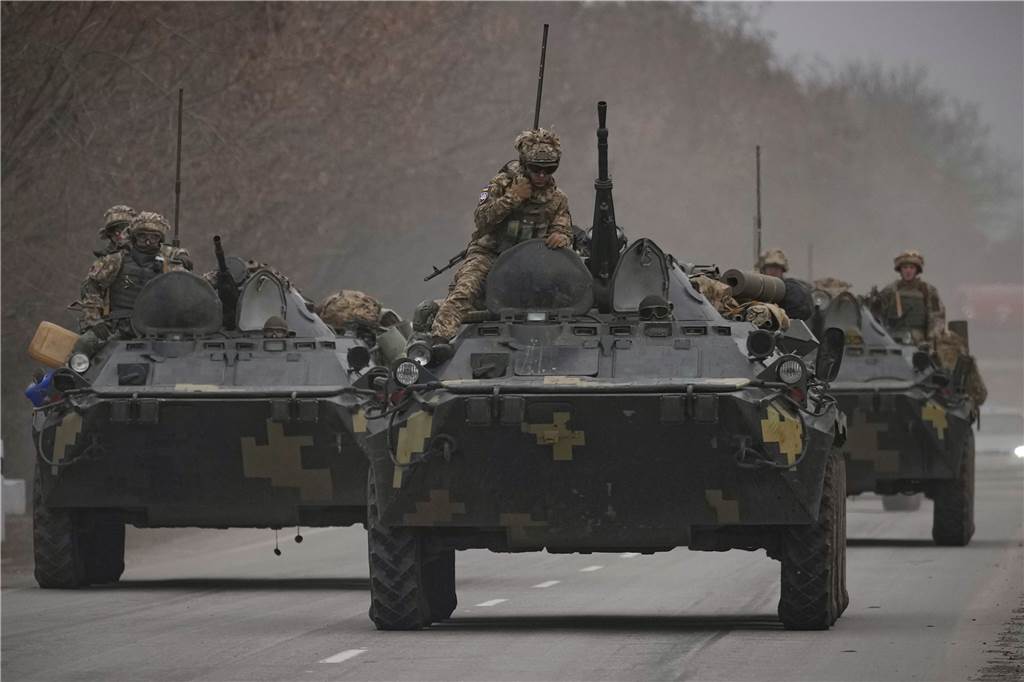 Ukrainische Soldaten sitzen auf gepanzerten Mannschaftstransportern, die auf einer Straße in der Region Donezk in der Ostukraine fahren.