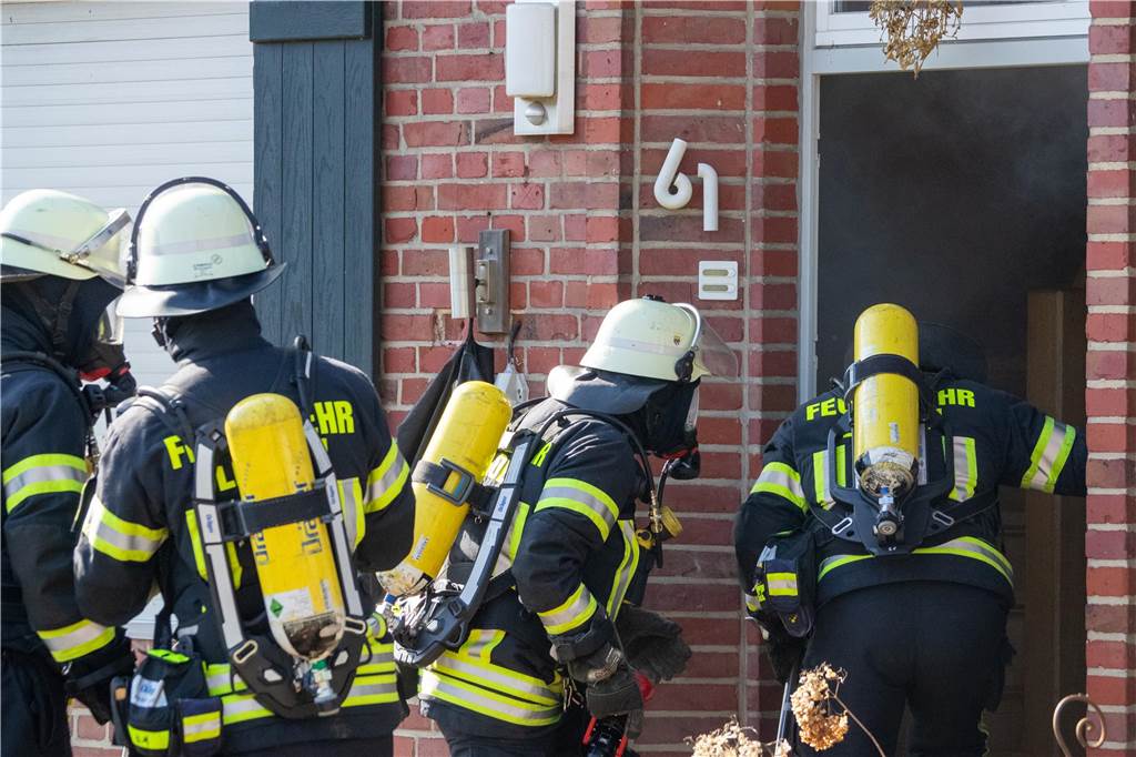 Übung: Feuer in Schreinerei, Menschen vermisst, Wasser wird knapp Vier Feuerwehrmänner mit Atemschutzgeräten vor einem Wohnhaus, in dem für Übungszwecke ein Brand simuliert wird.