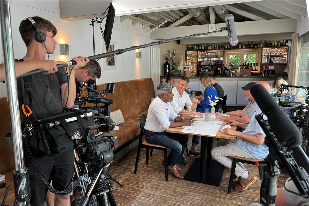 Auf dem Foto sitzen die vier Gäste von Marlen Kempf am Tisch. Sie werden von zwei Kameras gefilmt und ein Tonmann hält eine Mikrofon-Angel über ihren Köpfen.